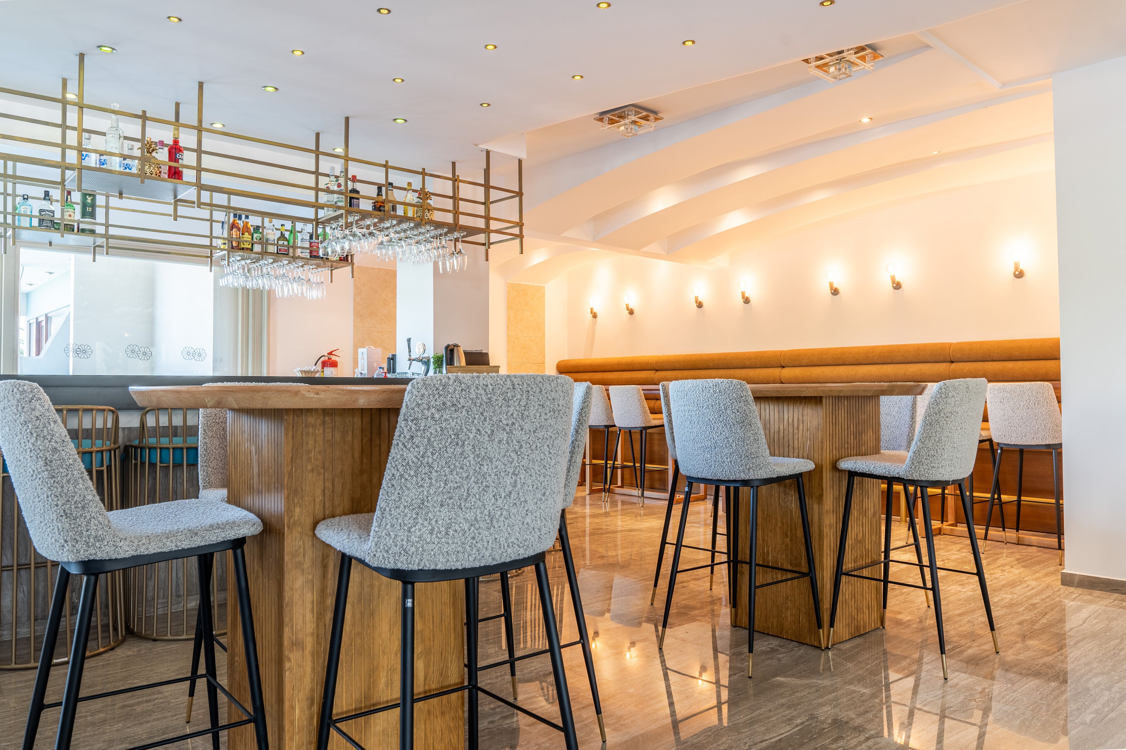 Un espace bar moderne avec des tabourets hauts, un comptoir en bois et un plafond décoratif agrémenté de luminaires suspendus.