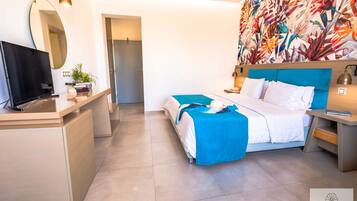 Una habitación de hotel moderna con una cama, mesitas de noche, un televisor y un gran papel tapiz tropical.