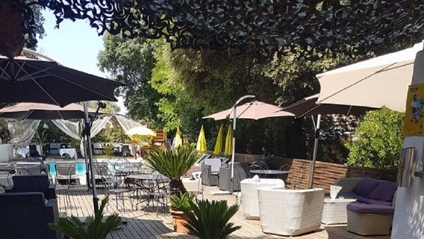 An outdoor patio area with stone flooring, outdoor seating, umbrellas, and potted plants. - Hotel La Maillane (Marseille)