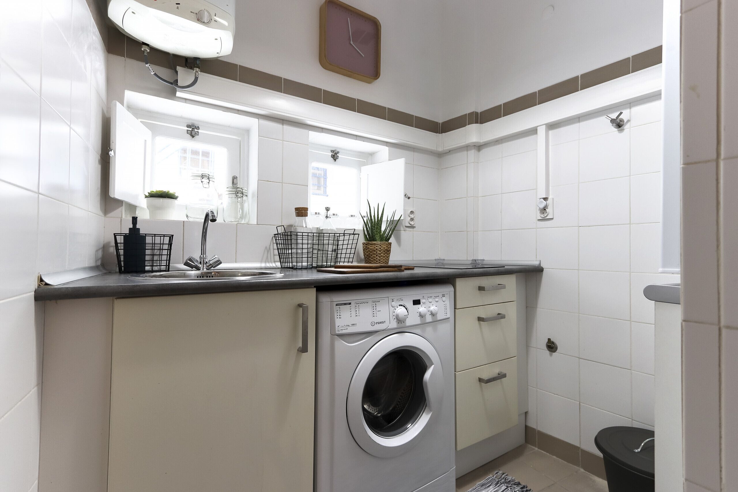 A compact kitchen with a built-in washing machine, a sink, and a small window.