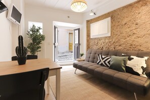 A modern living room with a brown sofa, a wooden dining table, and a cactus plant. - Golden Studio by Homing (Lisbon)