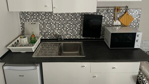 A kitchen with white cabinets, a black countertop, a sink, a microwave, and a dishwasher.