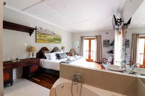 Una habitación de hotel con cama, mesita de noche, lámpara y un espejo grande.