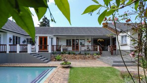 A two-story house with a swimming pool, a stone retaining wall, and a well-maintained lawn. - Arbour1 (George)
