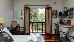A hotel room with a balcony, a desk, a bed, and a kitchenette. - Arbour1 (George)