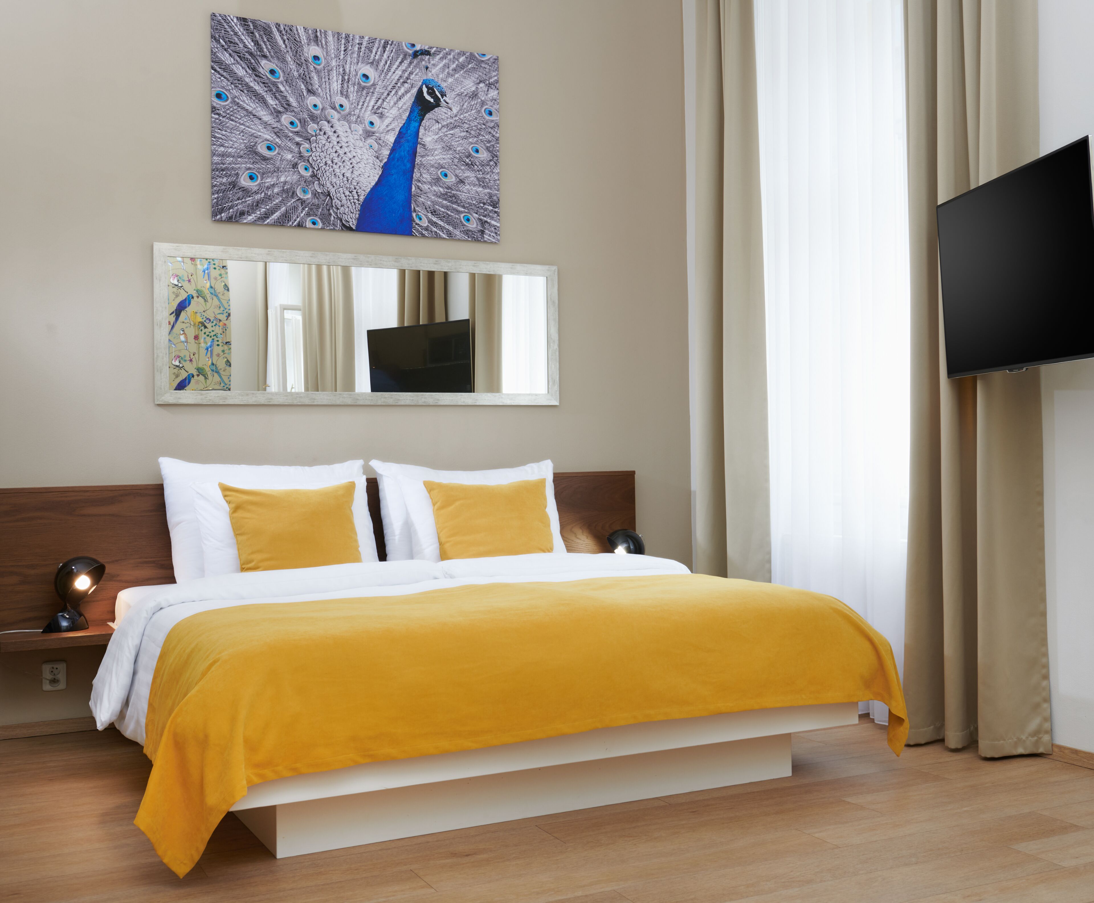 A hotel room with a bed, a television, and artwork on the wall.