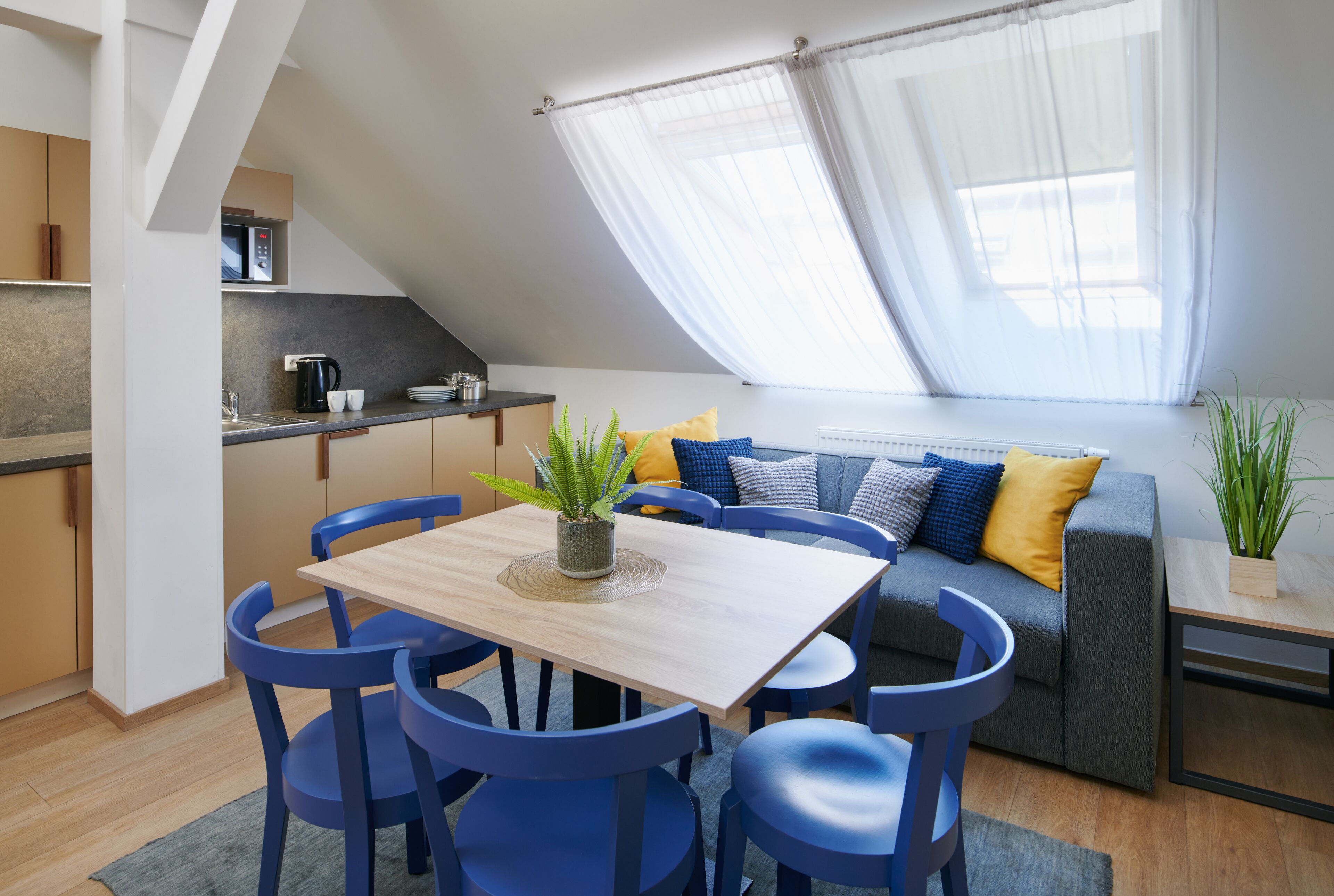 Un moderno loft con zona pranzo, angolo cottura e un'ampia finestra con tende leggere.