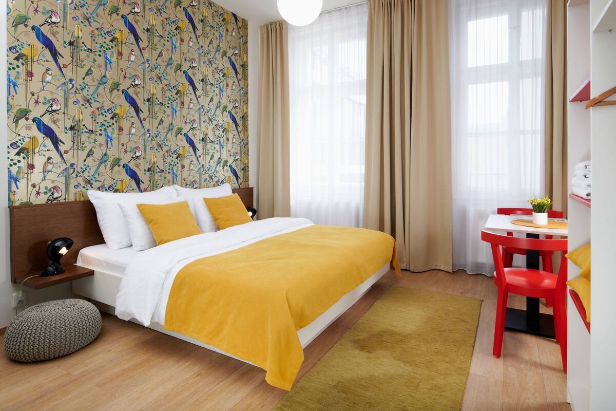 A neatly arranged hotel room with a bed, a desk, and a chair.