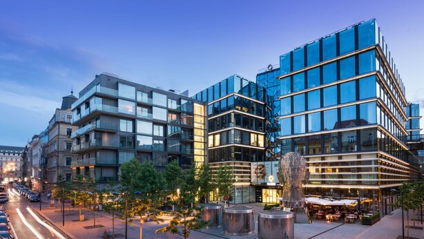 Un complexe immobilier urbain moderne, composé de plusieurs étages, doté de grandes fenêtres en verre et présentant un mélange de styles architecturaux.