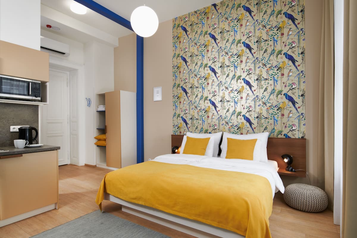 A modern bedroom with a bed, bedside table, and a wall with a bird pattern.