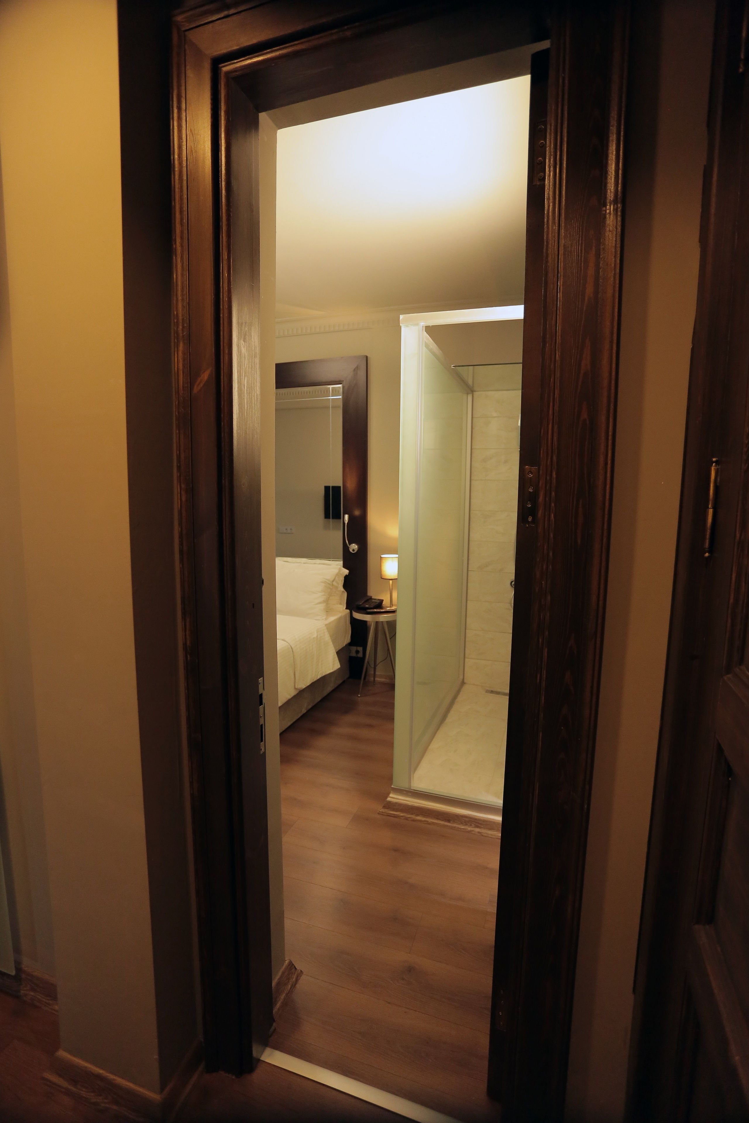 Une chambre d’hôtel comprenant un lit, une table de chevet, une lampe et un espace douche.