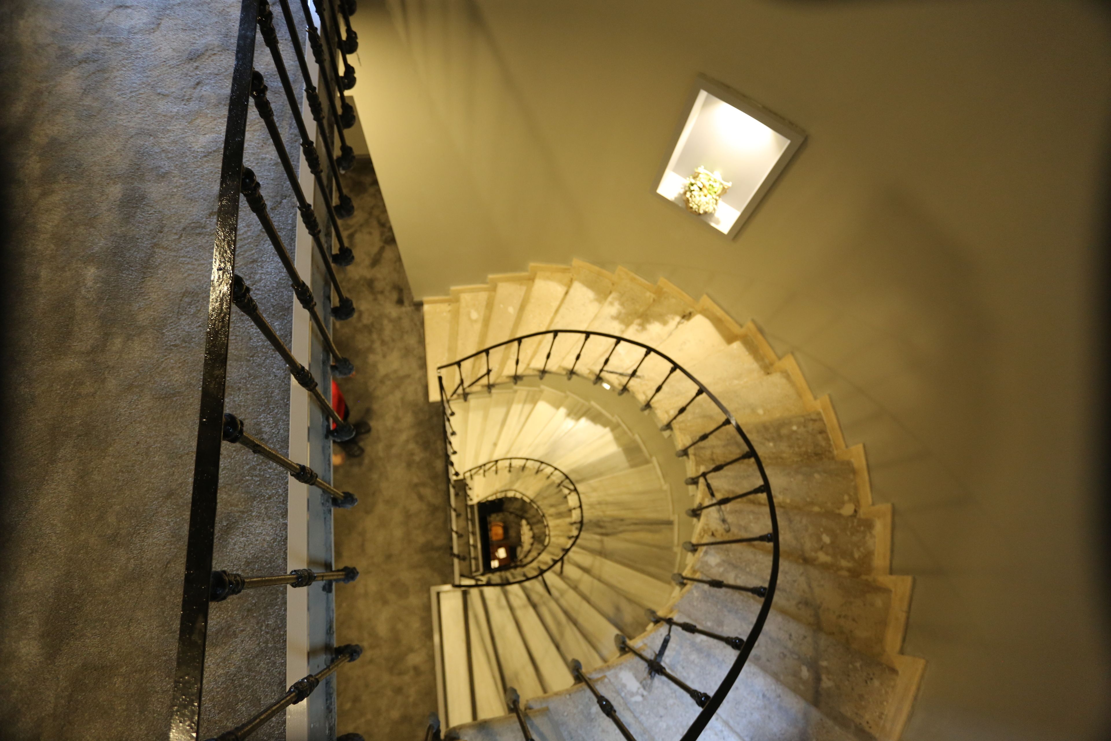 A spiral staircase with a handrail and a light fixture above it.