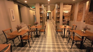 A hotel corridor with tiled flooring, wooden tables and chairs, and brick walls. - Ferman Pera (Istanbul)