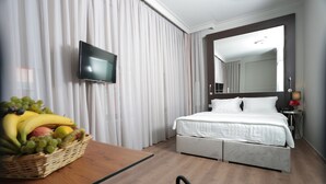 A hotel room with a bed, a TV, a wooden table with a fruit basket, and a large mirror. - Ferman Pera (Istanbul)