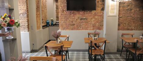 Un restaurante con paredes de ladrillo, una televisión de pantalla plana, mesas y sillas de madera y baldosas de suelo con diseños.