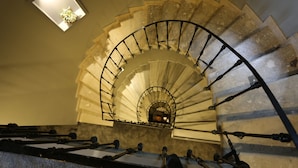 A spiral staircase with a metal railing, a small skylight, and a view of a room below. - Ferman Pera (Istanbul)
