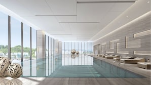 A modern indoor pool area with a glass barrier, lounge seating, and a view of the cityscape. - Primus Hotel Nanchang International Expo City (Nanchang)