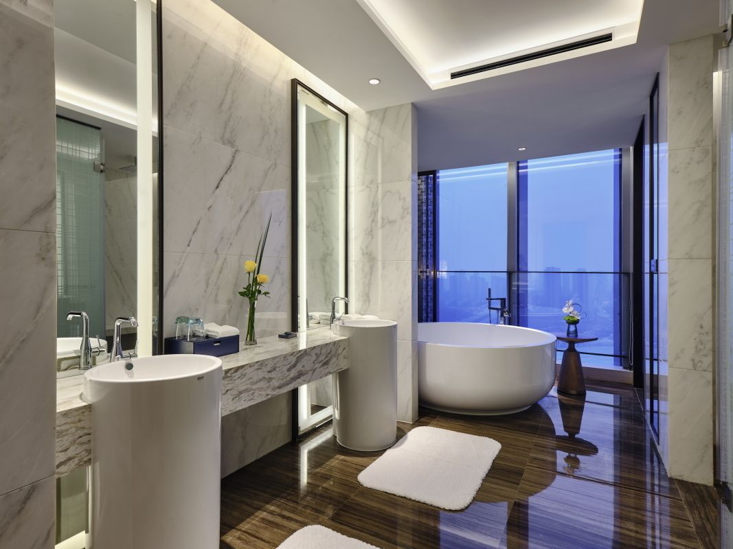 Un baño moderno con una bañera grande, dos lavamanos y un espejo amplio.