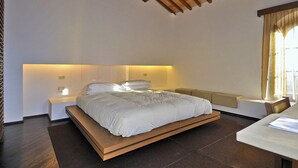 Un dormitorio moderno con una cama plataforma de madera, mesitas de noche y un banco.