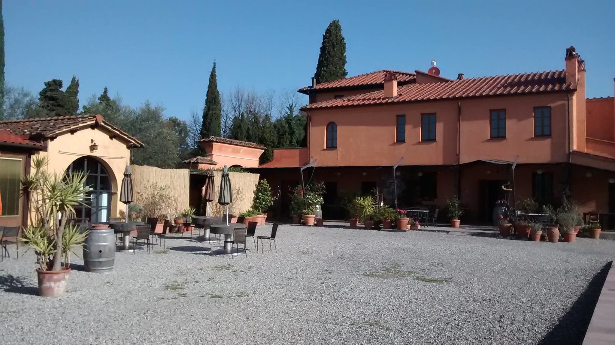 A courtyard with outdoor seating, potted plants, and a building with a tiled roof.