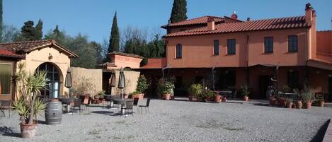 A courtyard with outdoor seating, potted plants, and a building with a tiled roof.