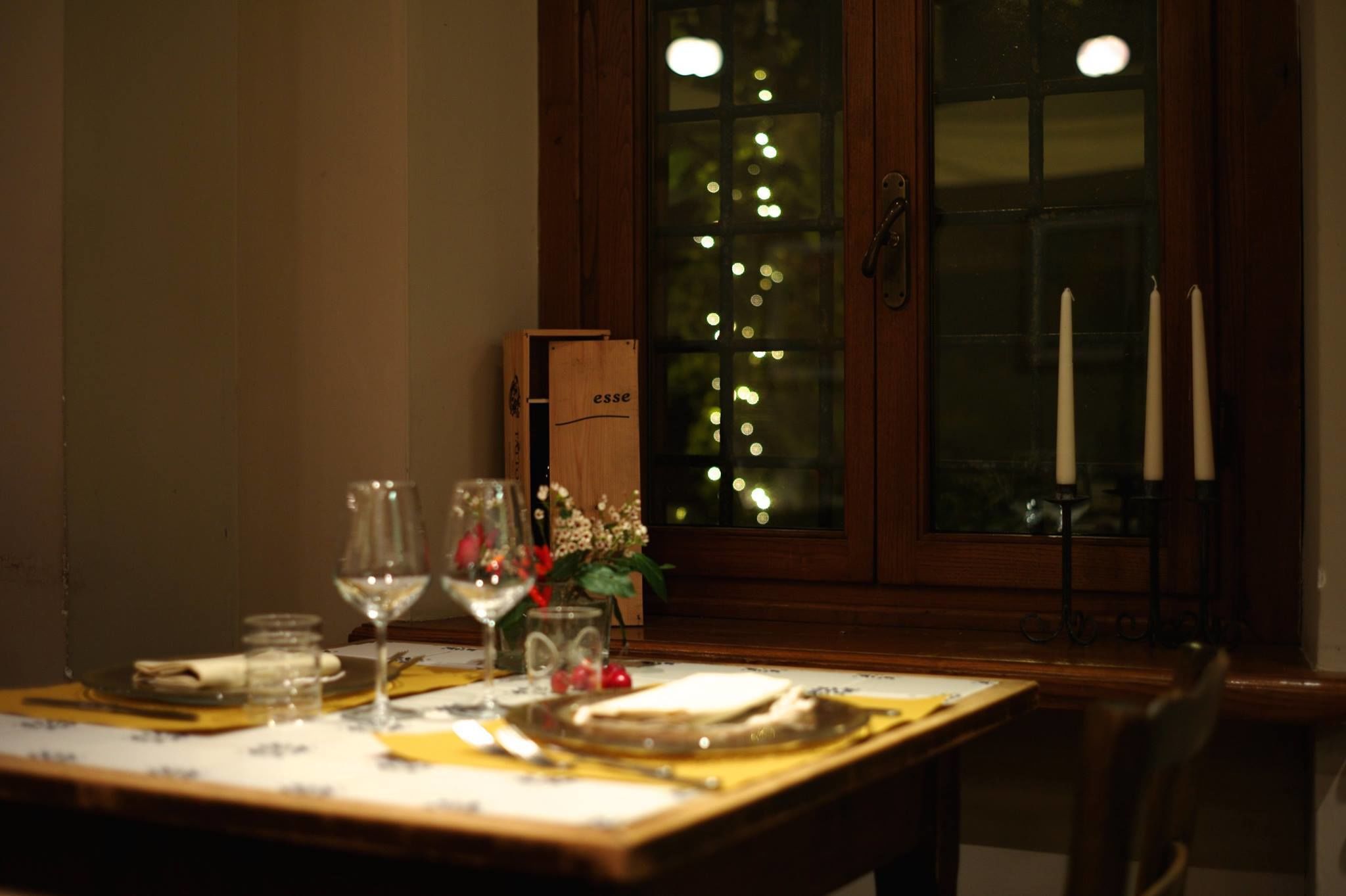 Mesa de comedor dispuesta con copas de vino, platos y un candelabro.