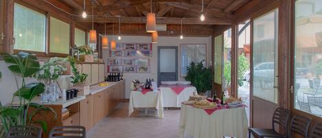 A spacious room with wooden beams, large windows, and tables set up for dining.