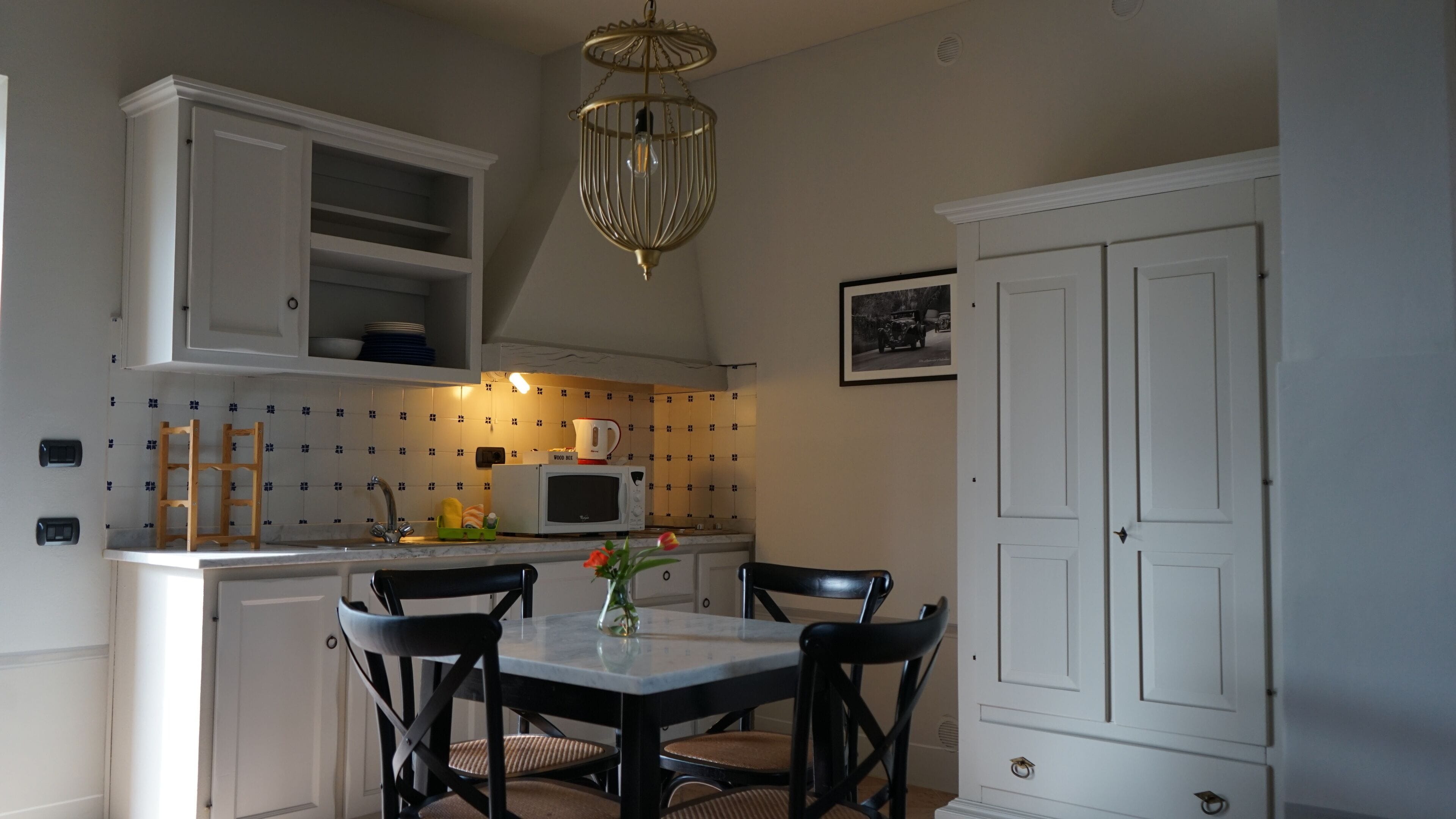 A kitchen with white cabinets, a microwave, a sink, and a dining table with chairs.