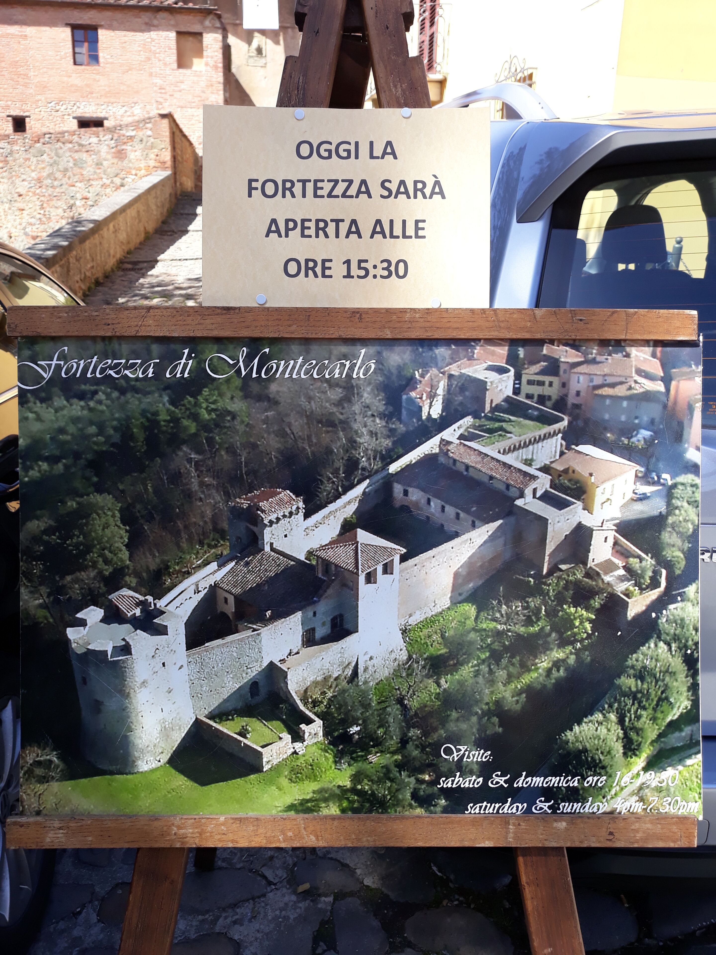 Un cartel con vista aérea de la Fortaleza de Montecarlo, que incluye los horarios de apertura.