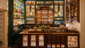 Un bar avec des étagères remplies de bouteilles d’alcool, une caisse enregistreuse et un comptoir où sont disposés des verres.