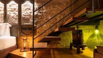 Un interior moderno con una escalera de madera, una cama y una pared de piedra.