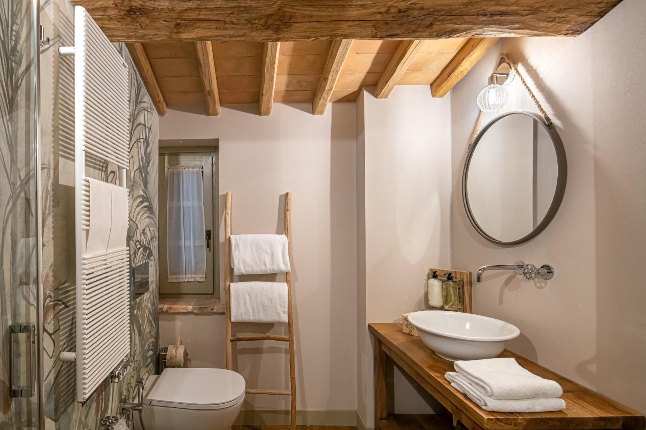 A bathroom with a wooden ceiling, a white sink, a mirror, and a towel rack.