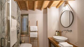 A bathroom with a wooden ceiling, a white sink, a mirror, and a towel rack.