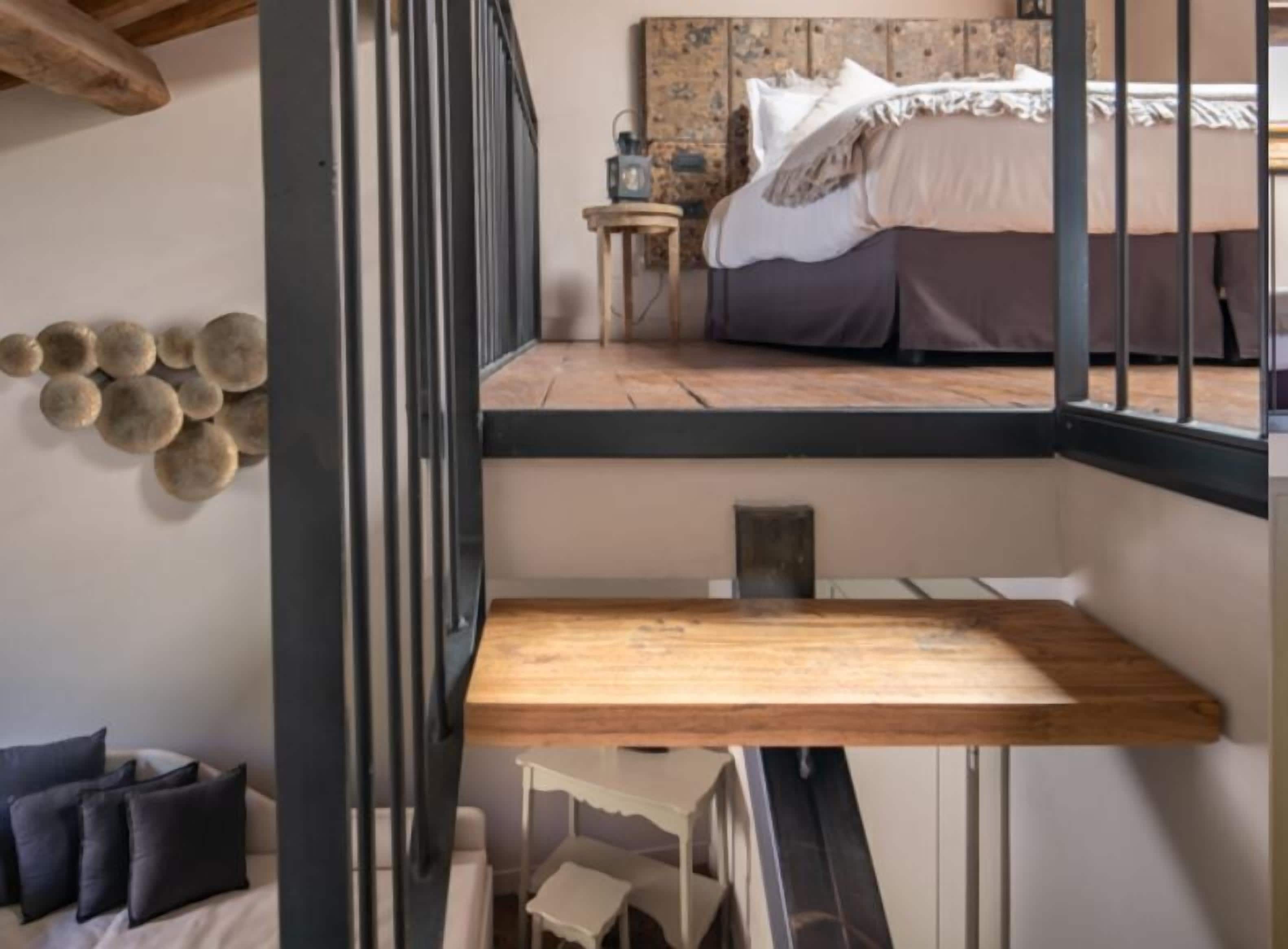 A bedroom with a bunk bed, a small bedside table, and a decorative wall.