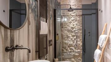 A modern bathroom with a large mirror, two sinks, a shower, and a wooden ladder.