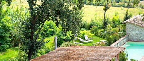 A rustic outdoor seating area with a stone pool and lush greenery.