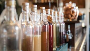 Diversas garrafas de vidro com etiquetas, provavelmente contendo diferentes bebidas, dispostas numa prateleira.