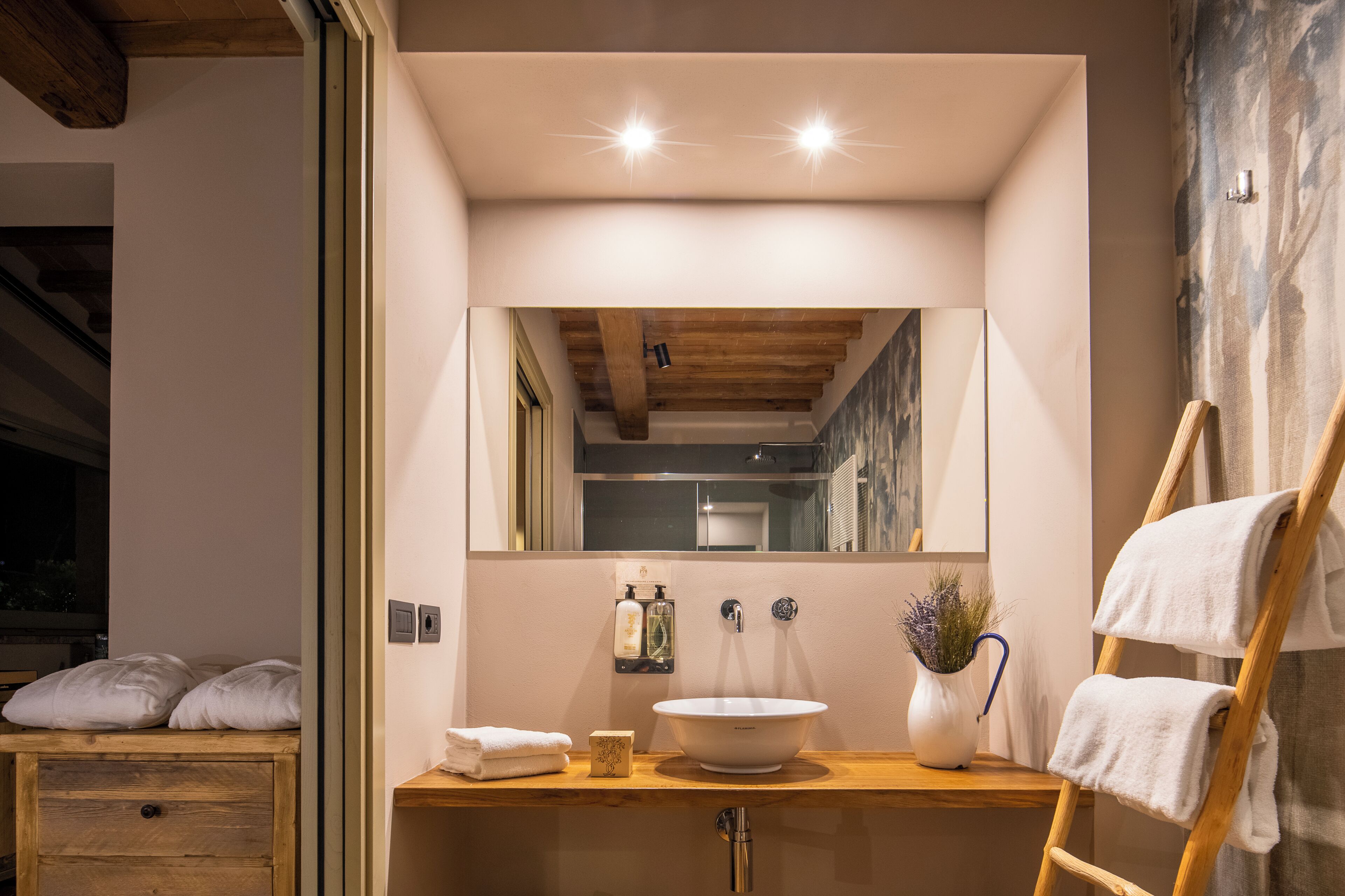 Une salle de bain avec un meuble-lavabo en bois, un grand miroir, un lavabo blanc et un porte-serviettes.