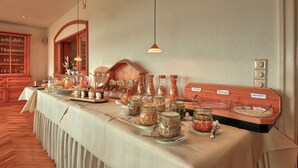 A buffet table with various food items and labels, wooden cabinets, and hanging pendant lights.