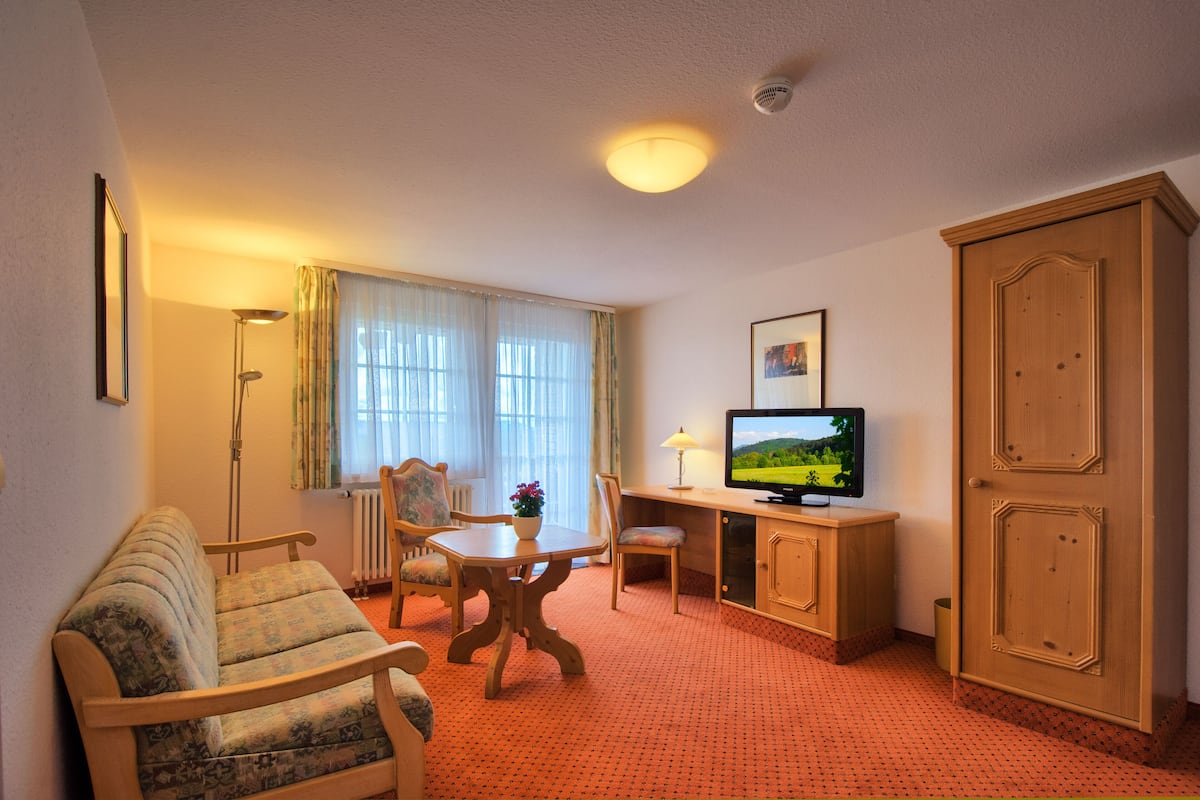 Une chambre d’hôtel équipée d’un canapé, d’une table à manger, d’un téléviseur et d’un meuble.
