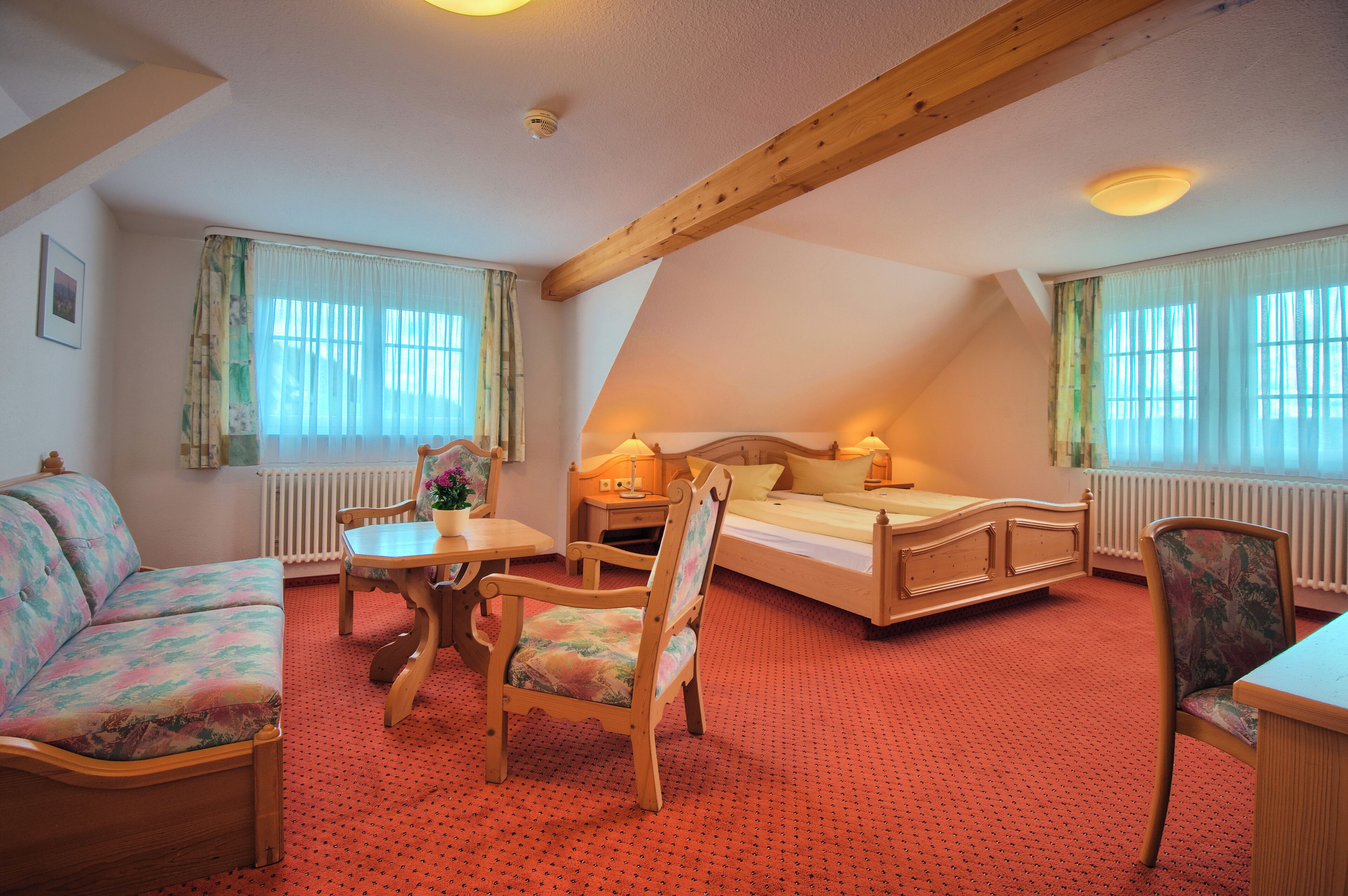 A cozy room with a bed, a sofa, a table, and chairs.