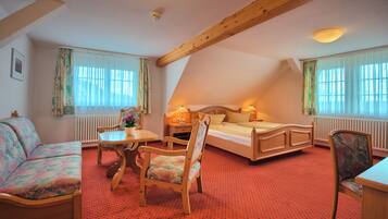 A cozy room with a bed, a sofa, a table, and chairs.