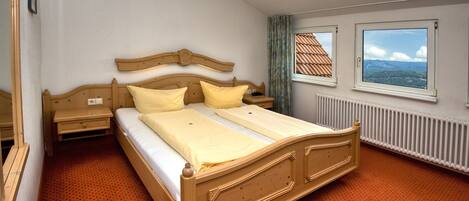 Ein Schlafzimmer mit einem Holzbett, zwei Fenstern, einer Heizung und einem roten Teppich.