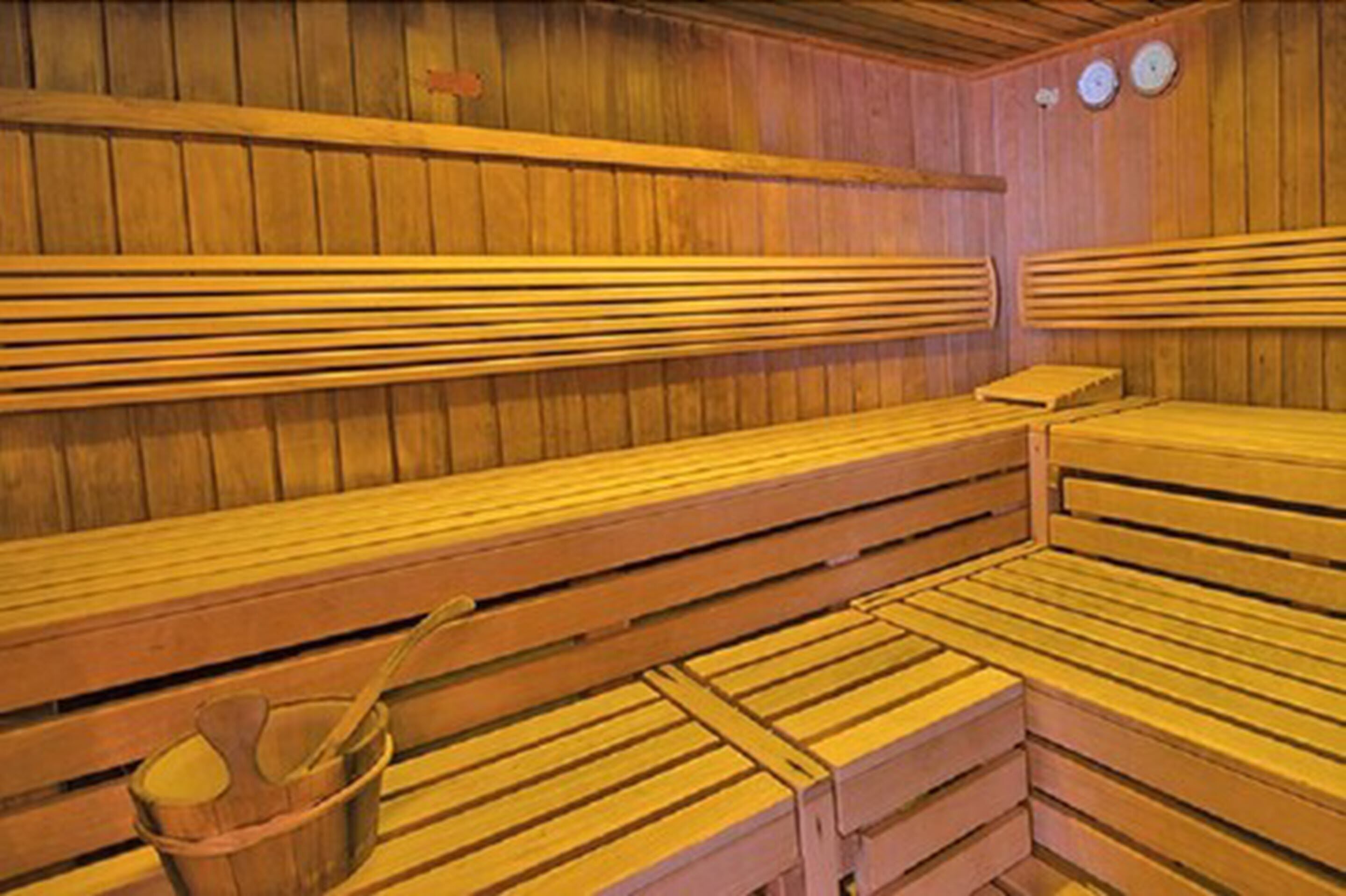 A sauna with wooden benches and a wooden bucket.