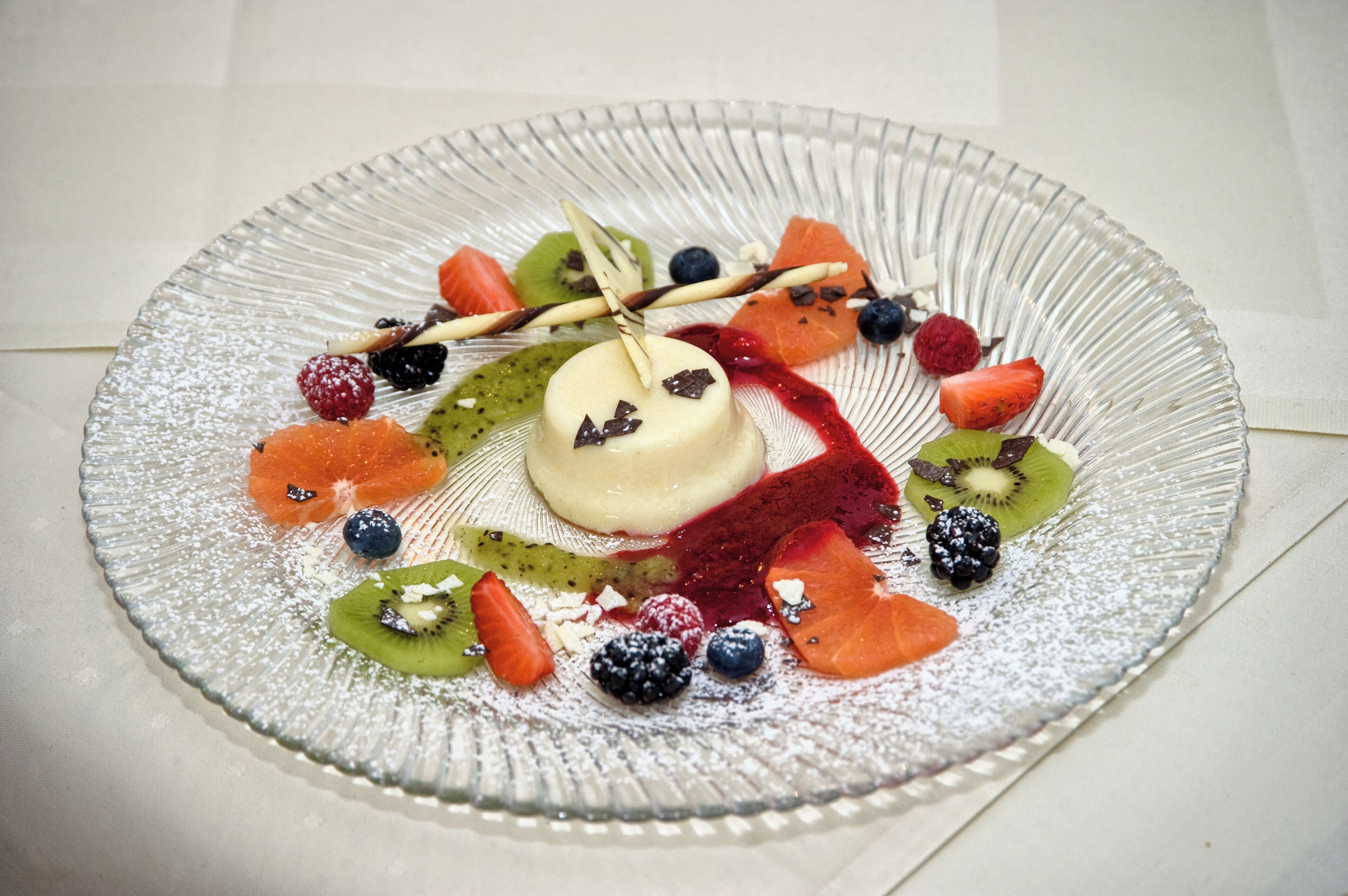 A dessert plate with a variety of fruits and a small dollop of cream.