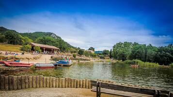 Zona junto al lago con barcos amarrados, una valla de madera y un pabellón.