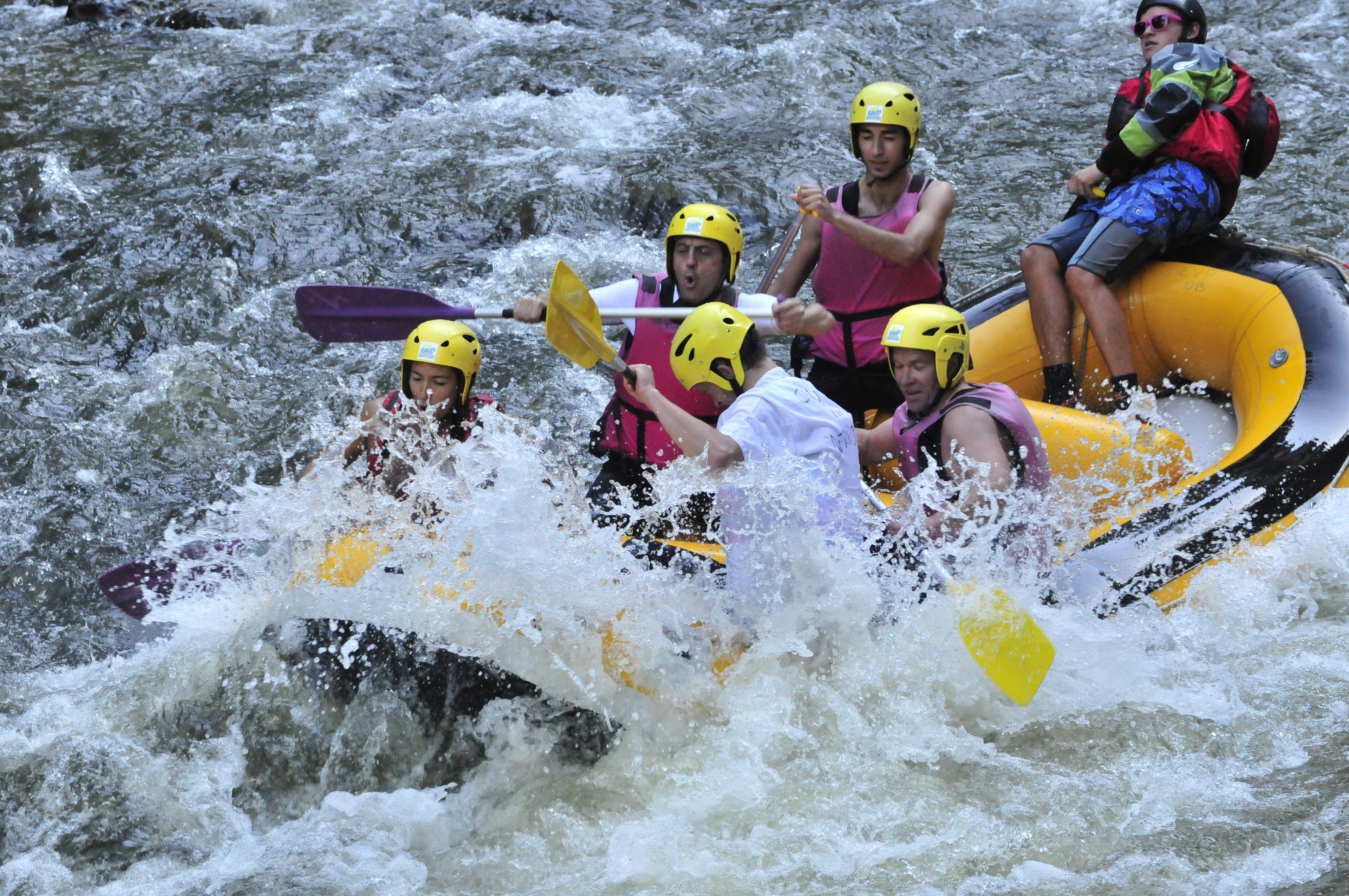 A group of people in a raft navigating through a river with rapids.