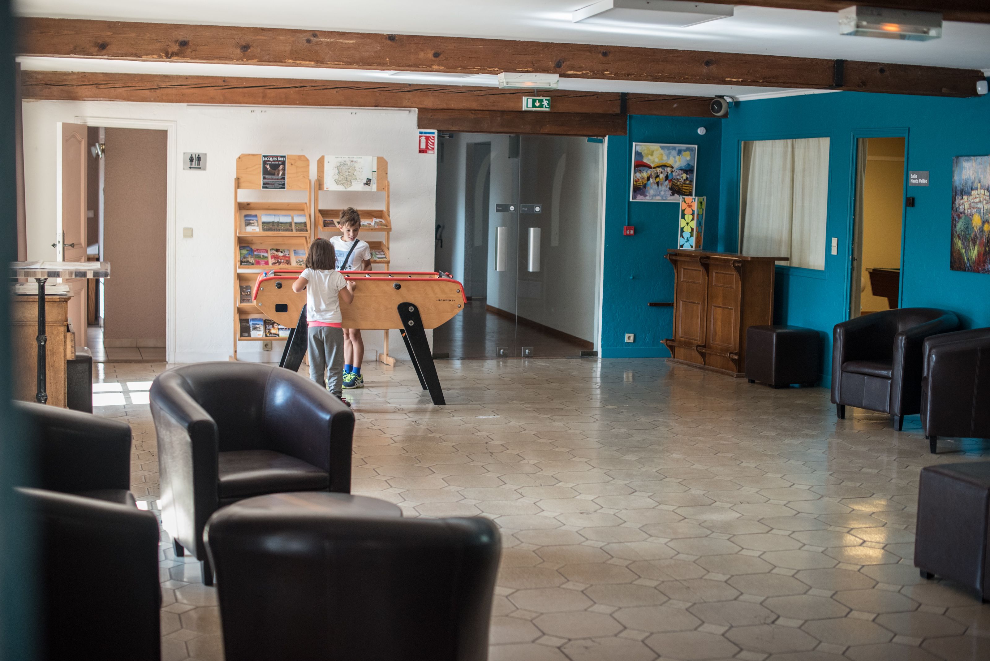 A spacious lobby with a wooden ceiling, a blue accent wall, and a seating area with leather chairs.