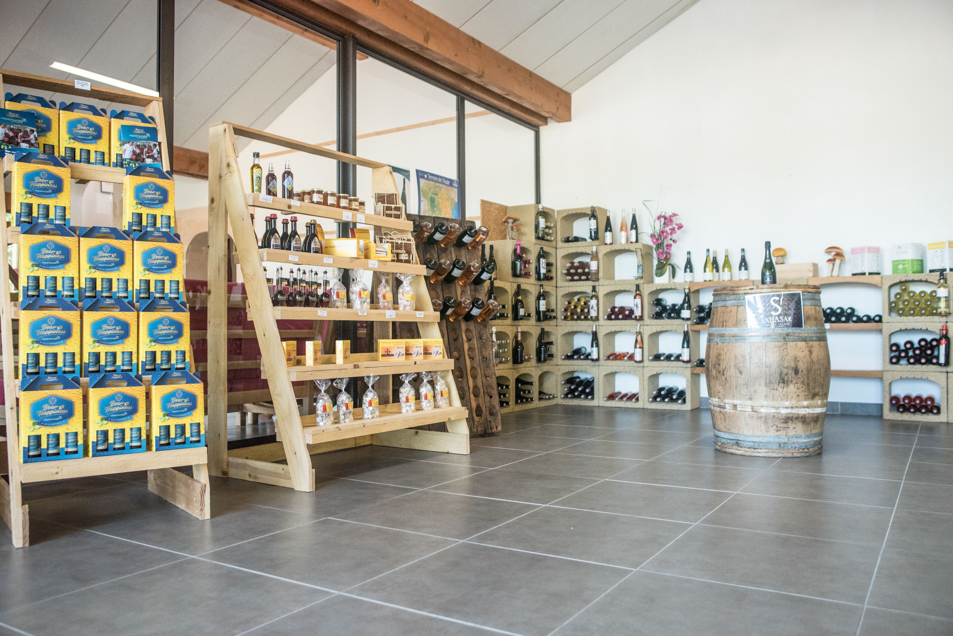 Une cave à vin avec des étagères et des présentoirs en bois où sont exposées différentes bouteilles et cartons de vin.
