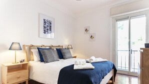 A bedroom with a bed, bedside tables, a lamp, and artwork on the wall. - Principe Real Balcony by Homing (Lisbon)